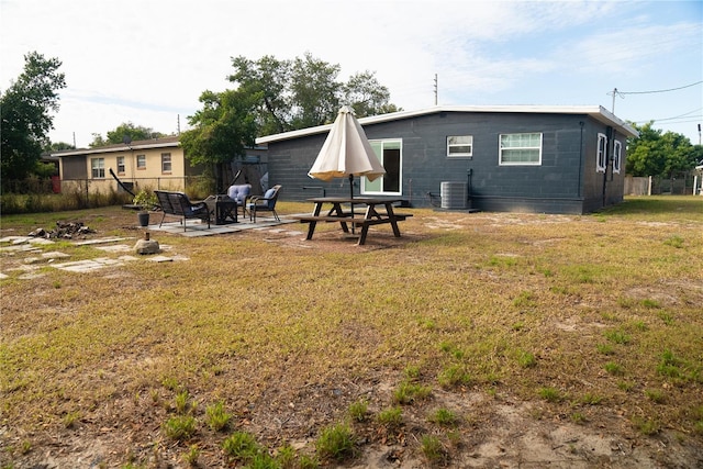 rear view of property featuring a patio area, central AC unit, and a lawn