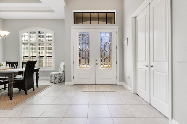 foyer featuring light tile patterned floors, baseboards, a notable chandelier, and french doors