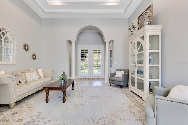 tiled living room with arched walkways, french doors, a raised ceiling, a high ceiling, and ornate columns