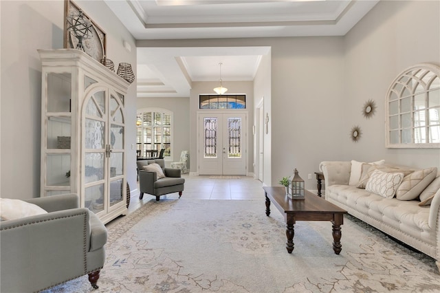 tiled living area with ornamental molding, a tray ceiling, and french doors