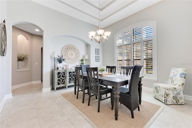 dining area with light tile patterned floors, baseboards, arched walkways, and an inviting chandelier