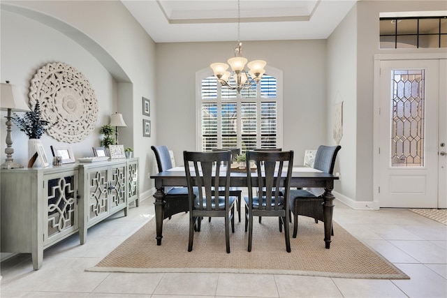 tiled dining area with a chandelier, a tray ceiling, and baseboards