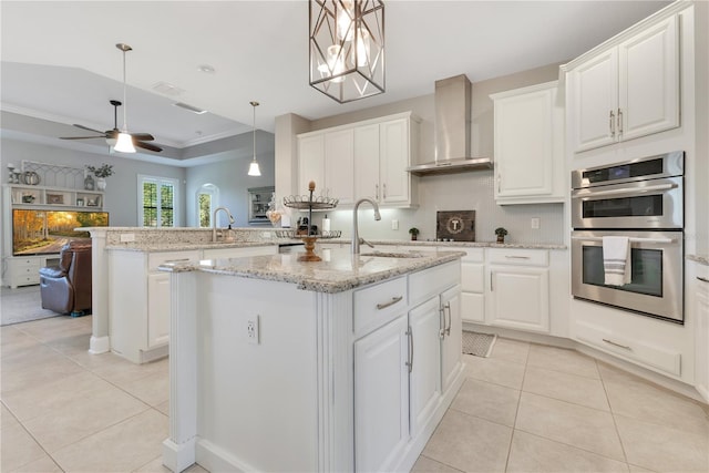 kitchen featuring double oven, light tile patterned flooring, a sink, and wall chimney range hood