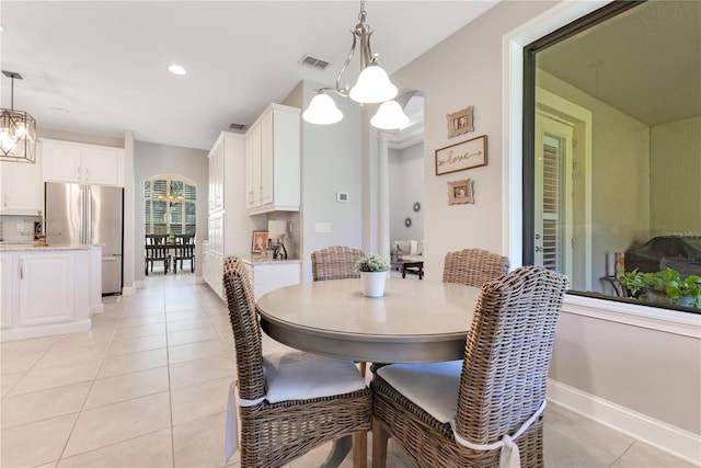 dining space with arched walkways, a notable chandelier, light tile patterned floors, recessed lighting, and baseboards