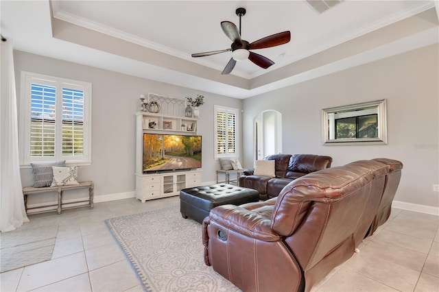 living area featuring a wealth of natural light, a tray ceiling, and arched walkways