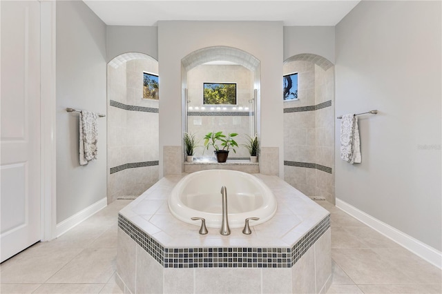 bathroom with a garden tub, tile patterned flooring, baseboards, and walk in shower