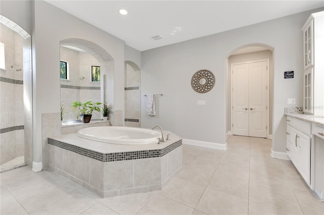 full bath featuring a walk in shower, a garden tub, vanity, and tile patterned floors