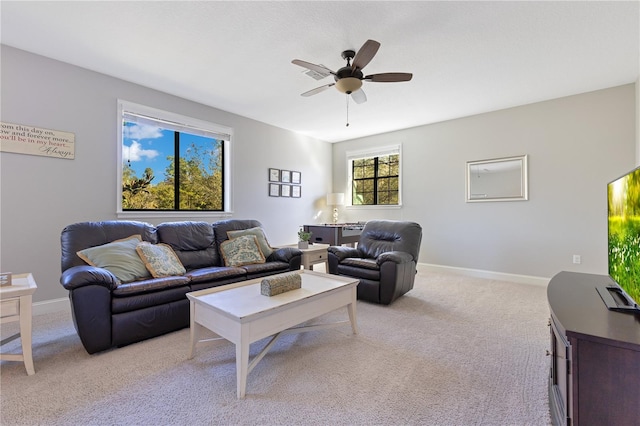 living area featuring light colored carpet, ceiling fan, and baseboards