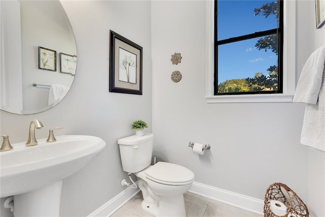 bathroom with baseboards, a sink, toilet, and tile patterned floors