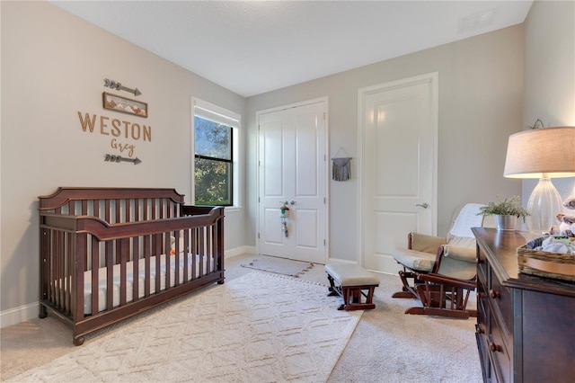 bedroom with carpet floors, visible vents, a crib, and baseboards