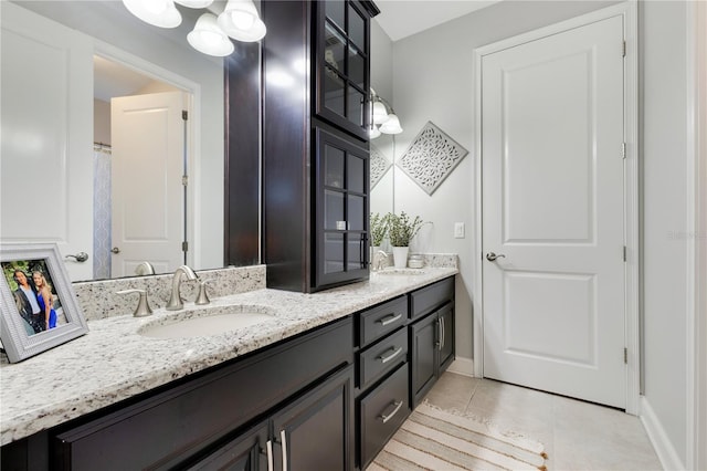 full bathroom featuring double vanity, baseboards, a sink, and tile patterned floors