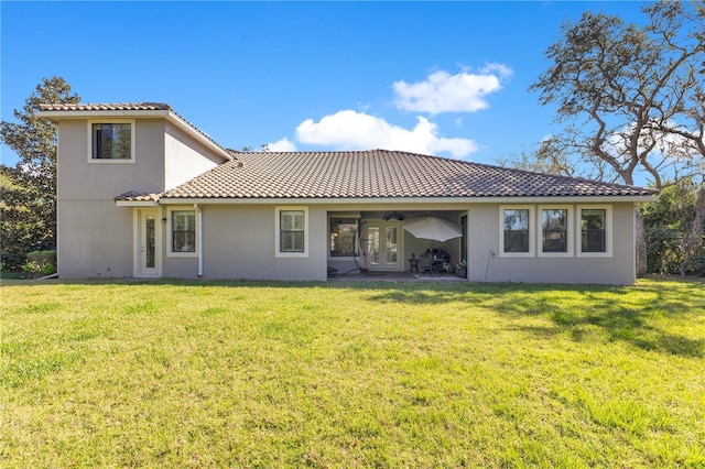 rear view of property featuring a yard, a patio, stucco siding, a ceiling fan, and a tiled roof