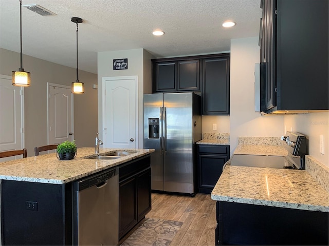 kitchen with visible vents, a sink, appliances with stainless steel finishes, light wood finished floors, and dark cabinets