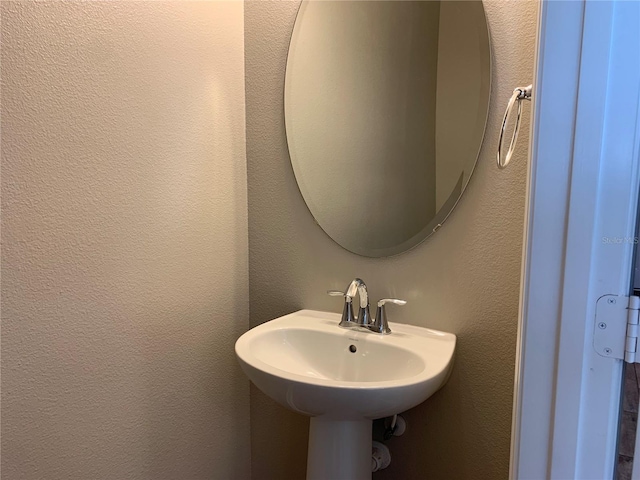 bathroom with a textured wall and a sink