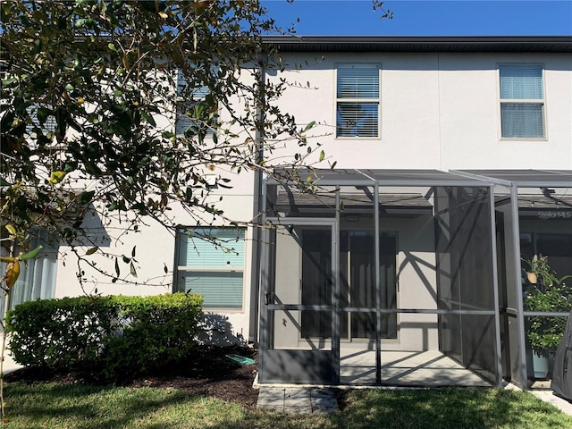 back of property featuring a lanai and stucco siding