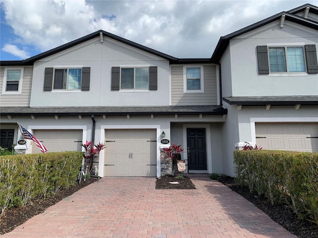 multi unit property with stucco siding, an attached garage, and decorative driveway