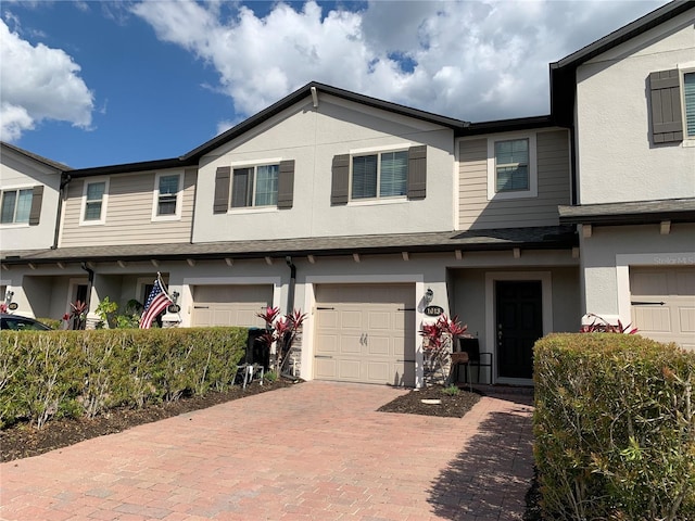 townhome / multi-family property with stucco siding, driveway, and a garage