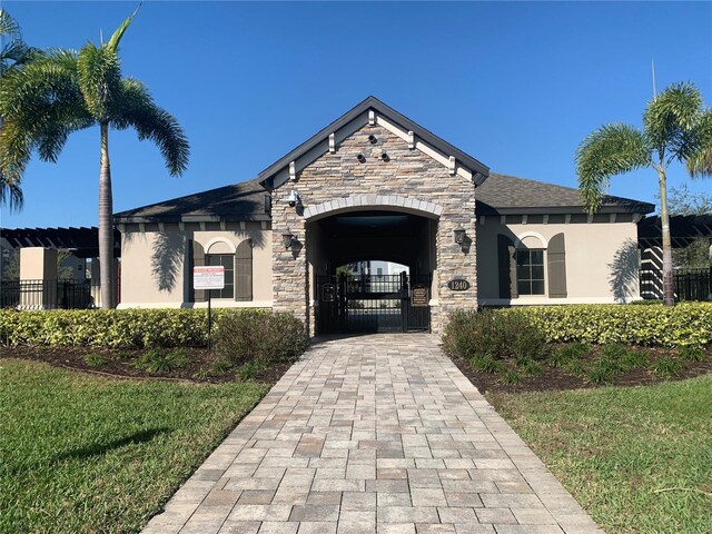 view of front of property featuring a gate, stucco siding, stone siding, and fence