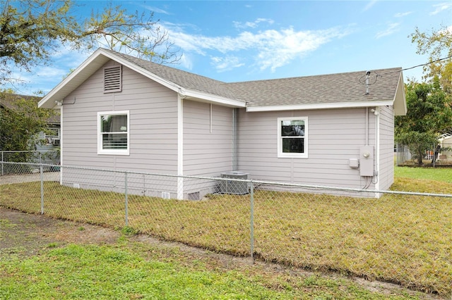 view of property exterior with roof with shingles, a yard, central AC unit, and fence