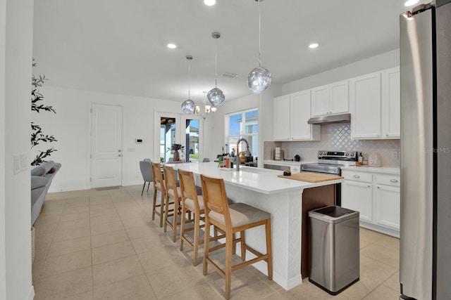 kitchen with tasteful backsplash, appliances with stainless steel finishes, light countertops, white cabinetry, and a sink