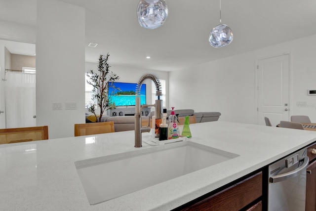 kitchen with open floor plan, a sink, light countertops, pendant lighting, and stainless steel dishwasher