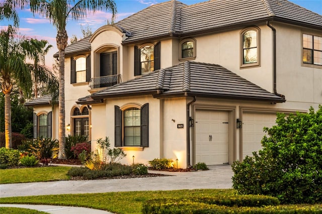 view of front of property with a garage, a tile roof, a balcony, and stucco siding