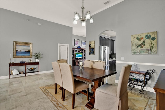 dining space featuring arched walkways, a notable chandelier, visible vents, baseboards, and marble finish floor