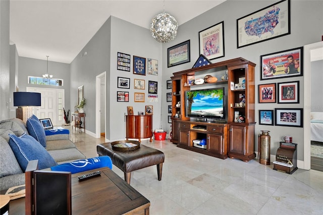 living area with baseboards, marble finish floor, a high ceiling, and a notable chandelier