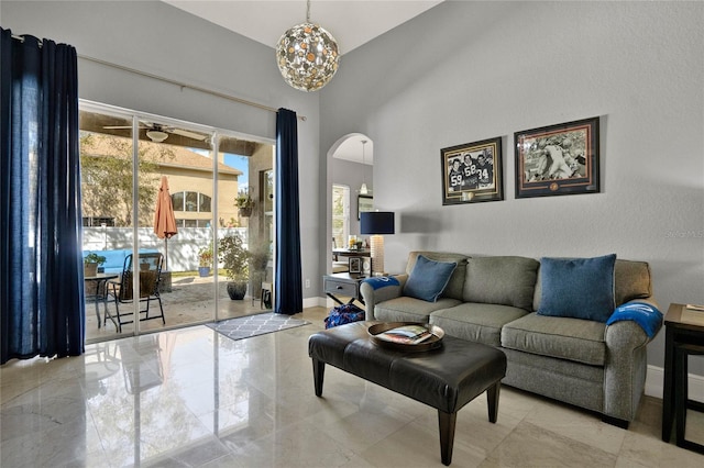 living area featuring arched walkways, marble finish floor, a towering ceiling, and baseboards