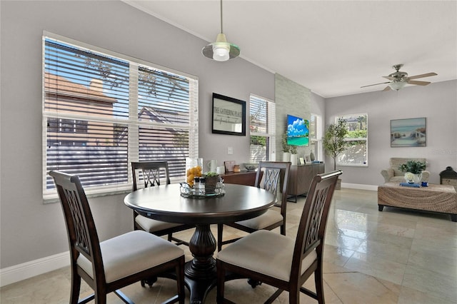 dining room featuring a ceiling fan, crown molding, and baseboards