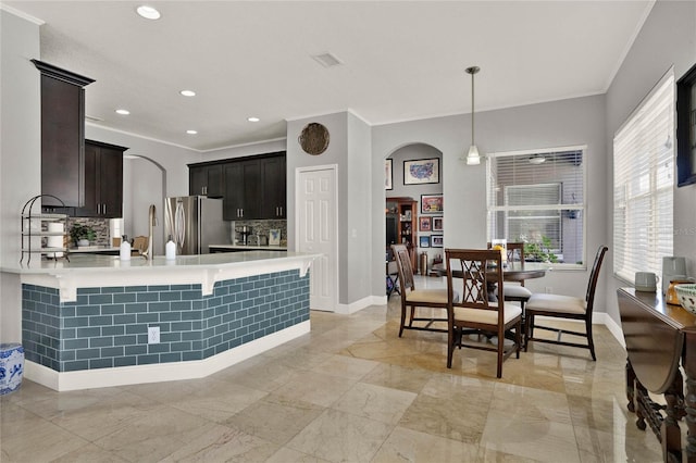 kitchen featuring arched walkways, a peninsula, light countertops, and freestanding refrigerator