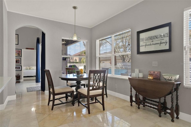 dining room featuring baseboards, arched walkways, and ornamental molding