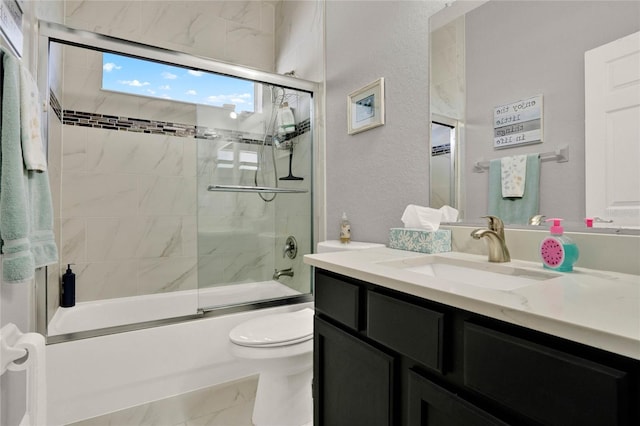 full bathroom with marble finish floor, a textured wall, toilet, combined bath / shower with glass door, and vanity