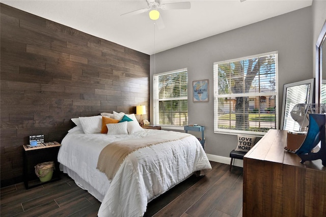 bedroom featuring wooden walls, wood finish floors, a ceiling fan, and baseboards