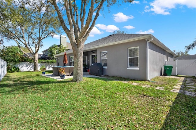 back of property featuring a fenced backyard, ceiling fan, a lawn, and stucco siding