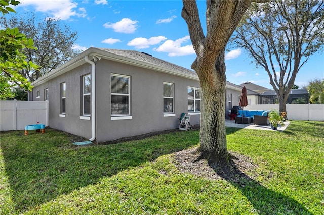 view of side of property with a lawn, an outdoor hangout area, fence, a patio area, and stucco siding