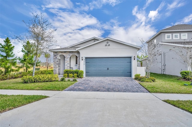 view of front facade featuring decorative driveway, stucco siding, a front yard, a garage, and stone siding