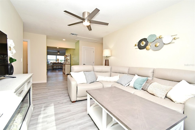 living room featuring light wood-style floors, ceiling fan, and visible vents