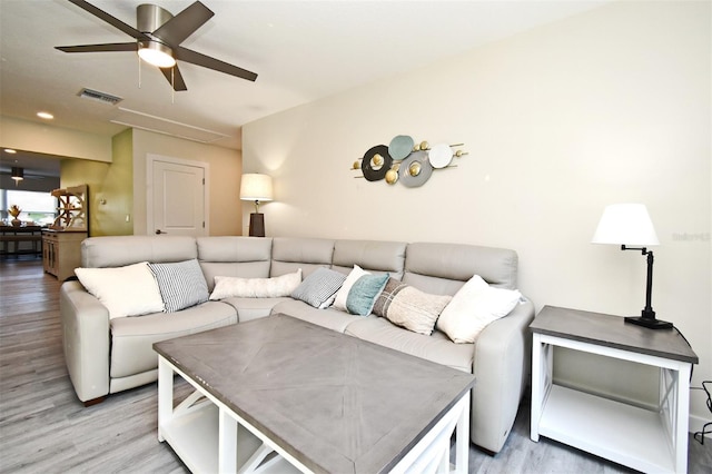 living room featuring a ceiling fan, attic access, visible vents, and light wood-style floors