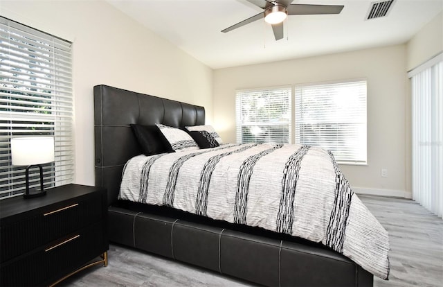 bedroom featuring light wood-type flooring, visible vents, ceiling fan, and baseboards