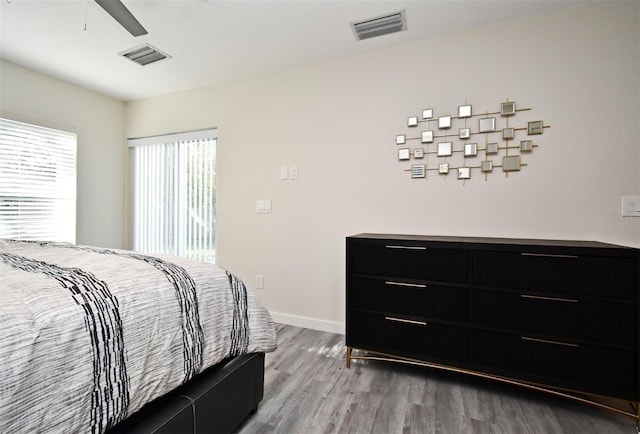 bedroom featuring a ceiling fan, visible vents, baseboards, and wood finished floors