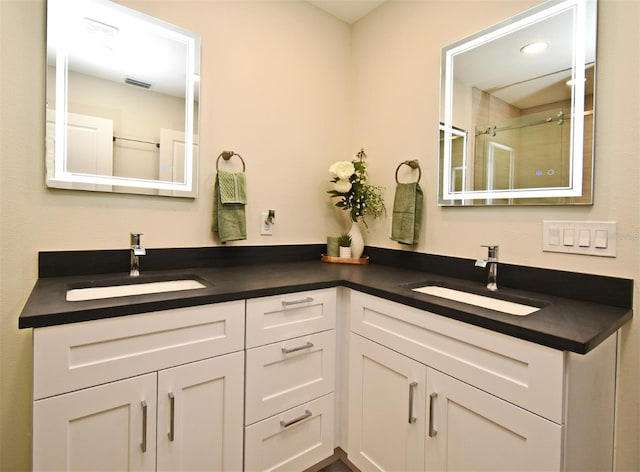 full bath featuring double vanity, visible vents, a sink, and an enclosed shower