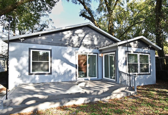 rear view of house with a wooden deck and stucco siding