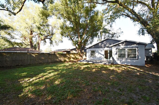 rear view of property with fence and a yard