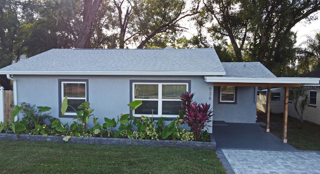 ranch-style house with a carport, roof with shingles, and stucco siding