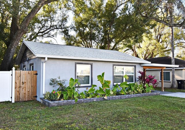 single story home with stucco siding, a shingled roof, fence, and a front yard