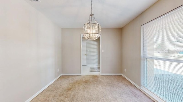 unfurnished room featuring baseboards, an inviting chandelier, and light colored carpet