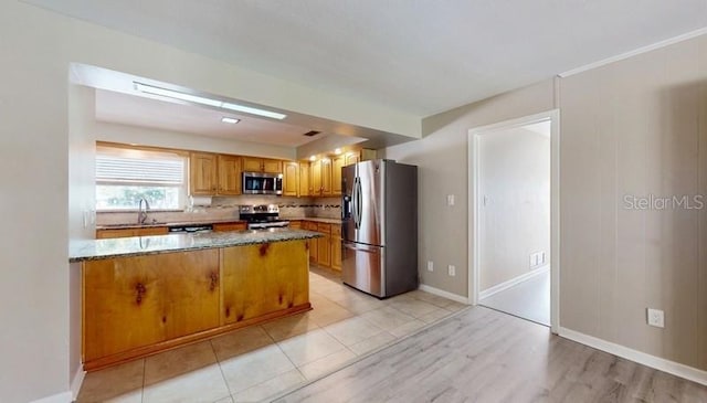 kitchen featuring tasteful backsplash, brown cabinetry, appliances with stainless steel finishes, dark stone countertops, and a peninsula