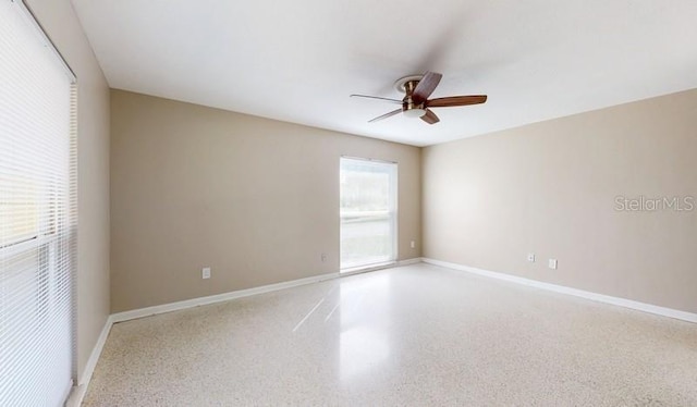 empty room with ceiling fan, baseboards, and speckled floor