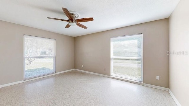 unfurnished room featuring ceiling fan, baseboards, a textured ceiling, and speckled floor